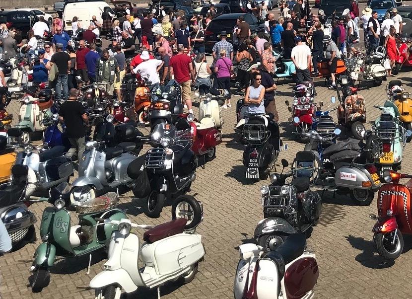 Groups of scooters and riders in a car park